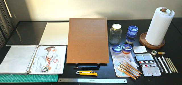 A spread of watercolor supplies, with a focus on larger papers and binders for storage.